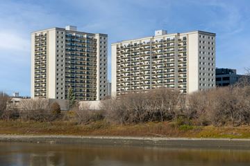 Winnipeg apartment for rent - Two identical buildings are situated next to a body of water.