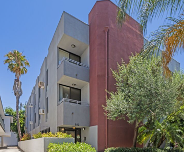 Los Angeles apartment for rent - A modern building with a red and grey facade and a balcony on the second floor.