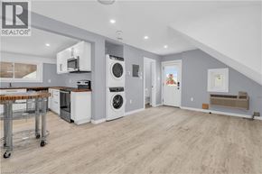 Kitchener house for rent - A well-lit, spacious laundry room with a washer and dryer, a dining table, and a kitchen area in the background.
