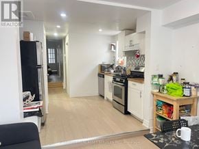 Toronto (University) house for rent - A kitchen with a black fridge, white cabinets, and a wooden island.