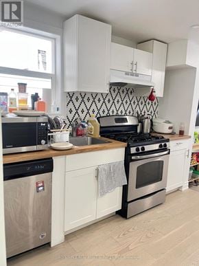 Toronto (University) house for rent - A kitchen with white cabinets and a black and white tiled backsplash.