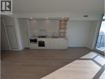 Coquitlam apartment for rent - A modern kitchen with white cabinets and a wooden floor.