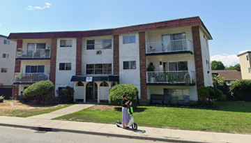 Kelowna apartment for rent - A person is riding a scooter in front of a building.