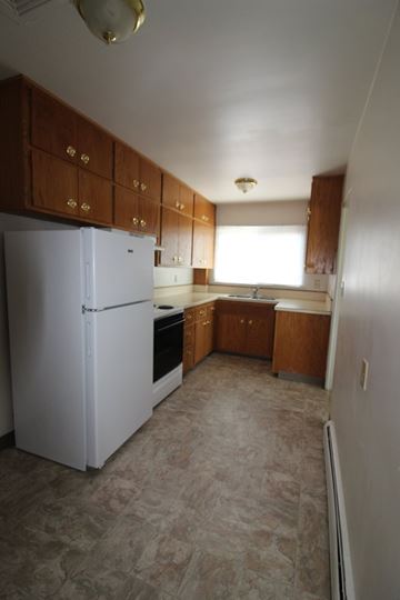 Moorhead apartment for rent - A kitchen with a white refrigerator and wooden cabinets.