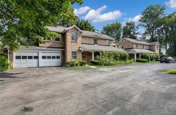 Buffalo apartment for rent - A large house with a garage is surrounded by trees.