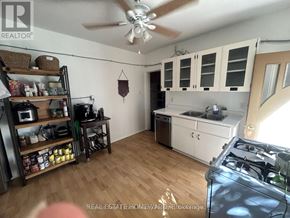 For rent in Toronto (Greenwood-Coxwell) - A kitchen with a wooden floor and white cabinets.
