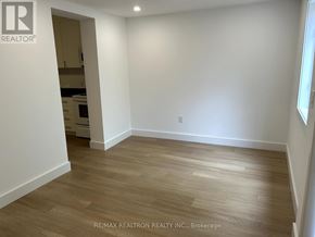 For rent in Toronto (Greenwood-Coxwell) - A room with wooden flooring and white walls, with a doorway leading to another room.