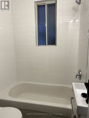 For rent in Toronto (Greenwood-Coxwell) - A white bathroom with a tub, toilet, and sink.