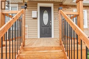 Stoney Creek house for rent - A wooden staircase with a black railing leads to a black door.
