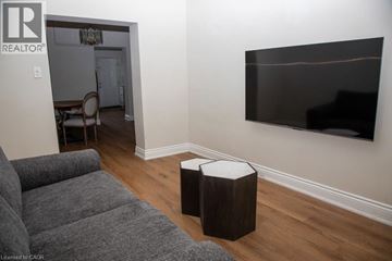 Hamilton townhouse for rent - A living room with a grey couch and a flat screen TV mounted on the wall.