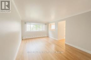 Ottawa multi-family for rent - A room with wooden flooring and a window showing a view of a building outside.