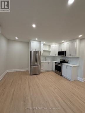 Toronto (Annex) house for rent - A kitchen with white cabinets and a wooden floor.