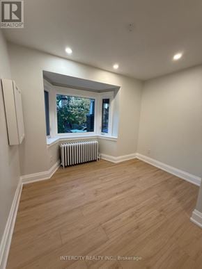 Toronto (Annex) house for rent - A room with wooden flooring and a window with a view of trees.