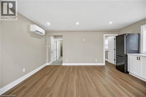 Hamilton apartment for rent - A spacious room with wooden flooring and a kitchen area with white cabinets and appliances.
