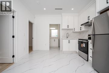 Vancouver house for rent - A modern kitchen with white cabinets and a marble floor.