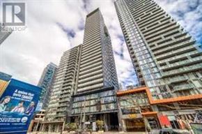 Toronto (Church-Yonge Corridor) condo for rent - A tall building with a glass facade stands in front of a construction site.