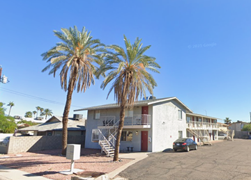 Mesa apartment for rent - A white building with a balcony and two palm trees in front.