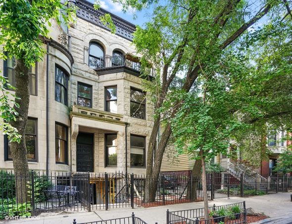 Chicago apartment for rent - A large, old building with a black iron fence in front.