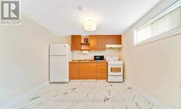 Toronto (Bendale) house for rent - A kitchen with a white fridge, orange cabinets, and a marble floor.