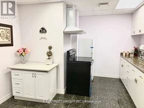 Richmond Hill (Rouge Woods) house for rent - A kitchen with a black fridge and white cabinets.