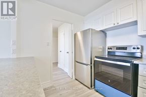 Barrie (Wellington) multi-family for rent - A kitchen with white cabinets and stainless steel appliances.