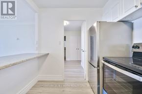 Barrie (Wellington) multi-family for rent - A kitchen with white cabinets and a stainless steel refrigerator.