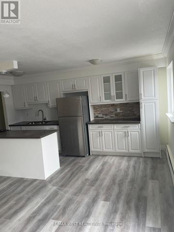 Oakville (Br Bronte) house for rent - A kitchen with white cabinets and a grey refrigerator.
