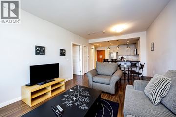 Vancouver apartment for rent - A living room with a grey couch and a wooden tv stand.