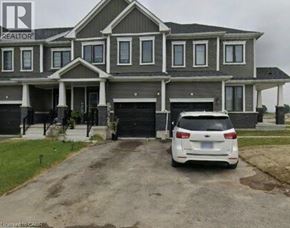Thorold townhouse for rent - A white car is parked in front of a grey house.