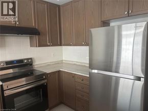 Thorold townhouse for rent - A kitchen with a stainless steel refrigerator, black stove, and wooden cabinets.