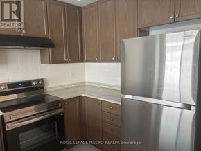 Thorold (Allanburg/Thorold South) townhouse for rent - A kitchen with a stainless steel refrigerator, black stove, and wooden cabinets.