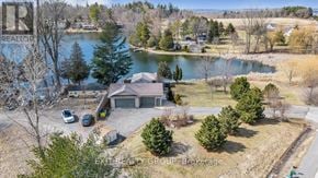 Quinte West (Sidney Ward) house for rent - A house with a garage is surrounded by trees and a body of water.