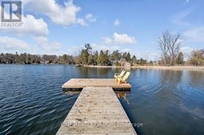 Quinte West (Sidney Ward) house for rent - A wooden dock extends into a lake with two yellow chairs on it.