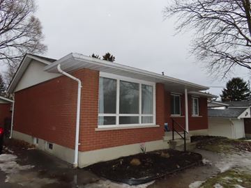 Guelph apartment for rent - A red brick house with a white roof and a small front yard.
