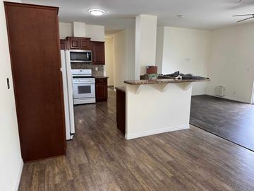 Bell Gardens apartment for rent - A kitchen with a refrigerator, microwave, oven, and a counter with a few items on it.