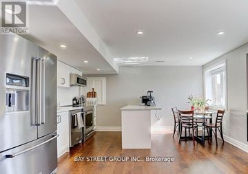 East Gwillimbury (Queensville) house for rent - A modern kitchen with stainless steel appliances and a dining table set for four.