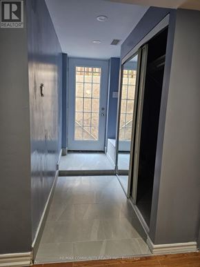 Toronto (Rouge) house for rent - A hallway with a blue door and a window in the background.