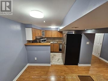 Toronto (Rouge) house for rent - A kitchen with a black refrigerator and wooden cabinets.