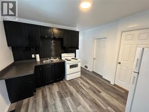 Windsor house for rent - A kitchen with black cabinets and a white stove top oven.