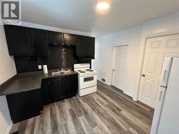 Windsor house for rent - A kitchen with black cabinets and a white stove top oven.