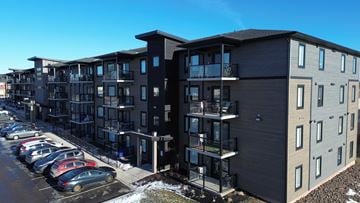 Moncton apartment for rent - A modern apartment complex with a parking lot in front.