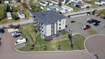 Moncton apartment for rent - A parking lot with cars and a building in the background.