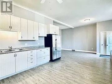 Welland (Lincoln/Crowland) fourplex for rent - A kitchen with white cabinets and a black refrigerator.