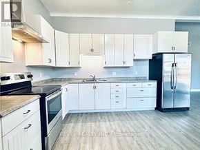 Welland (Lincoln/Crowland) fourplex for rent - A kitchen with white cabinets and a black refrigerator.