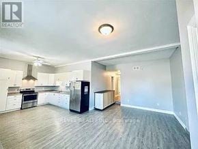 Welland (Lincoln/Crowland) fourplex for rent - A spacious kitchen with white cabinets and a black refrigerator.