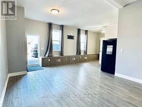 Welland (Lincoln/Crowland) fourplex for rent - A spacious room with wooden flooring and a black door on the right side.