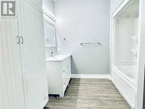 Welland (Lincoln/Crowland) fourplex for rent - A white bathroom with a sink, mirror, and a shower.
