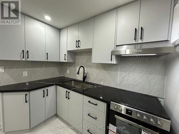 Toronto (Pleasant View) house for rent - A kitchen with white cabinets and black countertops.