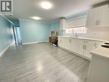 Vancouver house for rent - A kitchen with white cabinets and a grey floor.