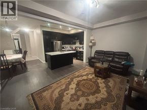 Hamilton townhouse for rent - A living room with a rug, a couch, and a kitchen area in the background.